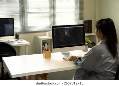 Female programmer coding on a desktop computer in a bright, modern office