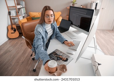 Female programmer with cup of coffee working at table in office