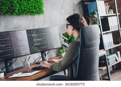 Female programmer focused on coding at a modern workspace with dual monitors