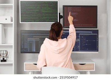 Female programmer working with computer at desk in office, back view