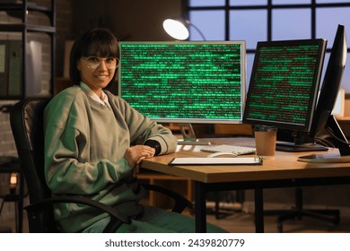 Female programmer working with computer monitors in office at night