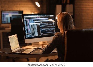 Female programmer working with computer in office at night