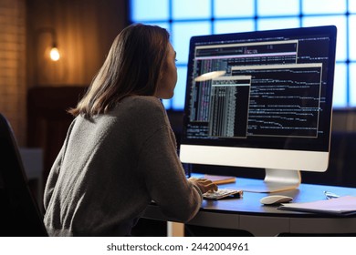Female programmer working with computer in office at night