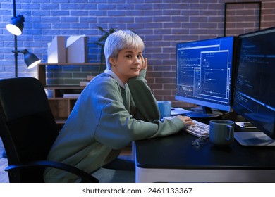 Female programmer working with computer in office at night