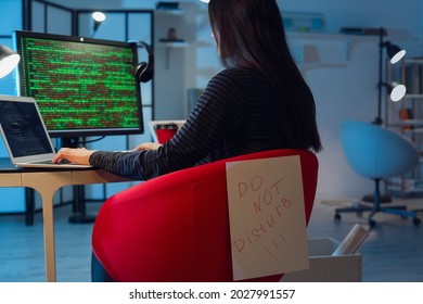 Female Programmer Working With Computer And Paper Sheet With Text DO NOT DISTURB In Office At Night