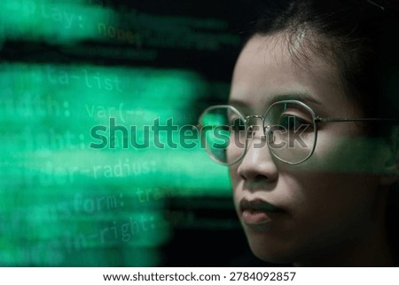 A female programmer working in a dark office environment while monitoring cybersecurity data and digital code on a computer screen. The scene represents software development, cyber technology, data analysis, and information security in a modern technology workspace.