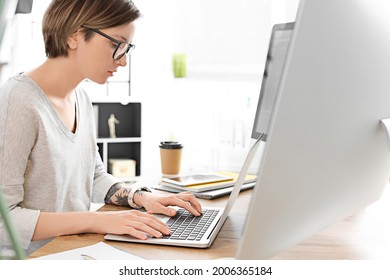 Female programmer working with laptop in office - Shutterstock ID 2006365184