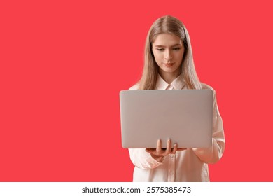 Female programmer working with laptop on red background
