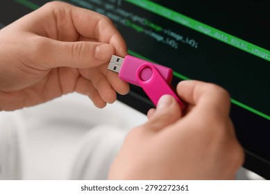 Female programmer's hands with USB flash drive in office, closeup