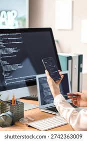 Female programmer's hands working with mobile phone in office, closeup