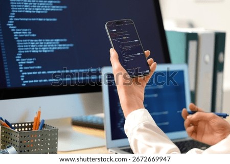 Female programmer's hands working with mobile phone in office, closeup