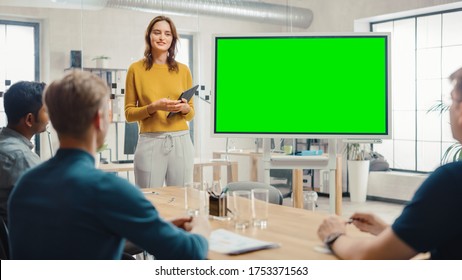 Female Project Manager Holds Meeting Presentation For A Team Of Developers. She Shows Green Screen Interactive Whiteboard Device For Business Planning Concept. Young People Work In Creative Office.