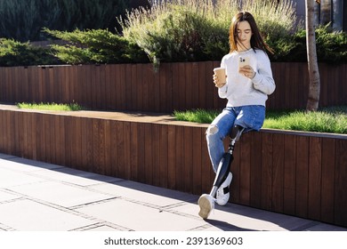 Female with prosthetic leg sitting in city. Disabled woman with prosthetic leg in red headphones, drinking coffee and using smartphone. Woman with leg prosthesis equipment. - Powered by Shutterstock