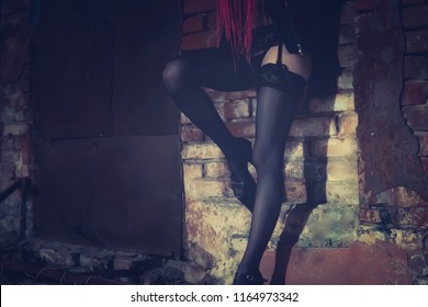 Female Prostitute Working On The Night Street. Sexy Girl Stands At The Old Brick Wall Bending Her Leg In A Seductive Pose.