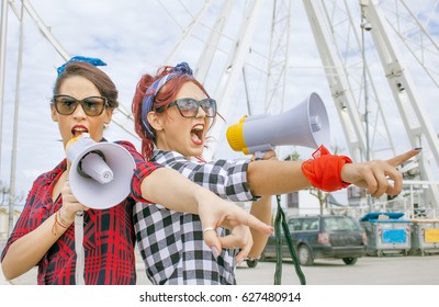 Female Protesters At Workers Day Rally Shouting Political Slogans With Megaphone Loudspeakers Wearing Red. Concept Of Activism Defending Jobs And Workers Rights