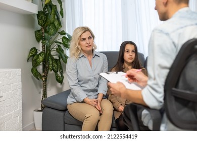 Female Psychologist Counseling Parent. Serious Single Mom And Sad Unhappy Child Sitting On Sofa And Discussing Social Behaviour, ADHD Disorder Diagnosis, Apathy Or Adolescent Depression With Therapist