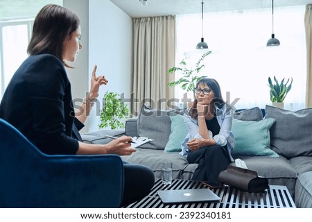 Female psychologist having therapy with middle-aged woman patient in office