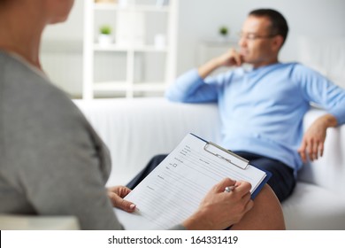 Female psychologist making notes during psychological therapy session