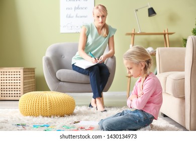Female psychologist working with naughty little girl in office