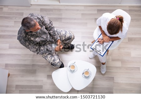 Female Psychologist Writing Down Notes During Counseling Session With Army Officer