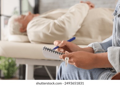 Female psychologist writing in notebook during hypnosis session in office, closeup - Powered by Shutterstock