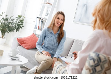 Female psychologyst therapy session with client indoors sitting girl smiling cheerful - Powered by Shutterstock