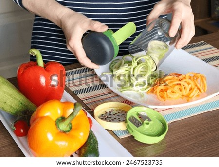 Female pull sliced vegetables from container of vegetable chopper in kitchen. Healthy food. 