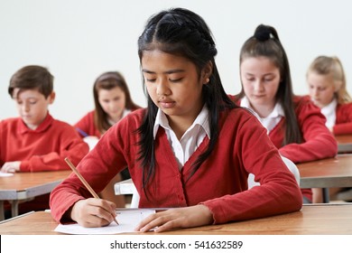 Female Pupil At Desk Taking School Exam 