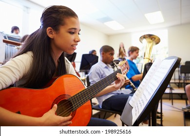 Female Pupil Playing Guitar In High School Orchestra - Powered by Shutterstock