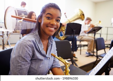 Female Pupil Playing Saxophone In High School Orchestra