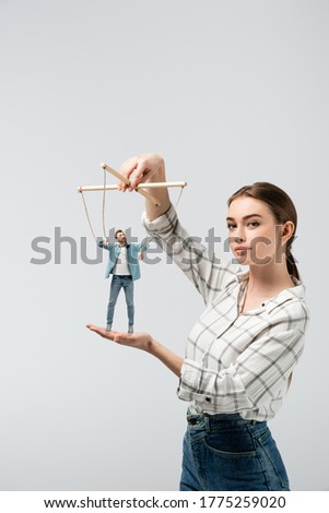 female puppeteer holding male marionette isolated on grey
