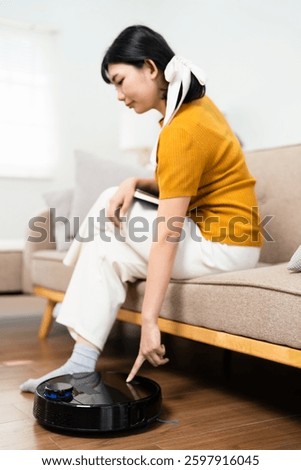female push start button on robot vacuum cleaner. Modern smart household. woman turns on smart vacuum robot pushing its button. Robotic vacuum cleaner on floor in living room.