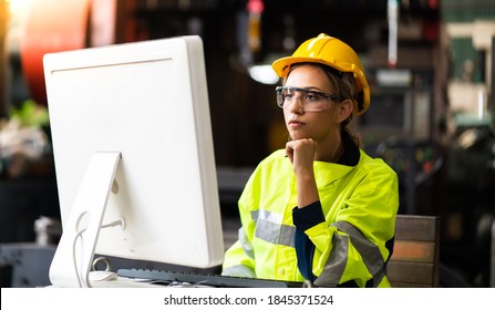 Female Quality Control Inspector Checking Workers At Factory. Woman Engineer With Yellow Hard Hat Helmet Working On Desktop Computer Inside Factory