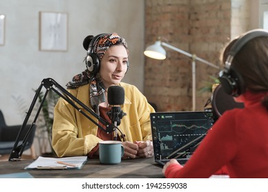 Female Radio Dj In Headphones Speaking In Microphone And Interviewing A Guest During Air On Radio