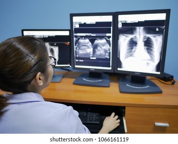 Female Radiologist Looking Attentively At One Of X-ray Images For Diagnosis  In Lab From Computer