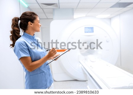 Female radiologist standing inside MRI scanning room.