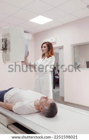 a female radiologist technician sets up a rengen device to conduct a medical test and an X-ray of a man in the laboratory
