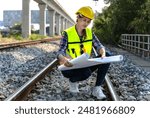 Female railway engineer looking at blueprint working in rail track