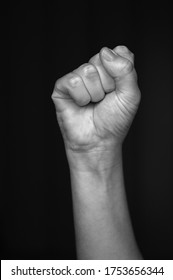 Female raised fist isolated on black background. The clenched fist, is a symbol of solidarity and support.It is also used as a salute to express unity, strength, defiance, or resistance.