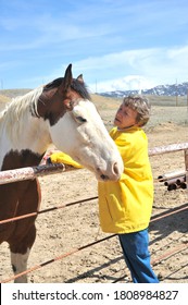 Female Rancher Bonding With Horse In Stable Outside.