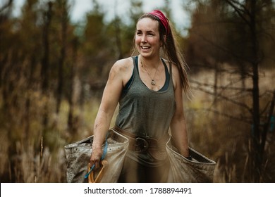 Female Ranger Planting Trees In Forest. Woman Tree Planter Carrying Bags Full Of Trees.