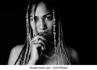 Female Rapper Biting Chain In Front Of Black Background