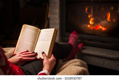 Female Reading A Book By The Fireplace. Cozy Winter Lifestyle