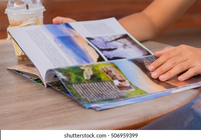 Female Reading A Magazine And Drink Ice Coffee On Wooden Table.