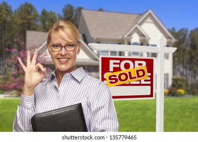 Female Real Estate Agent In Front Of Sold Home For Sale Sign And House.