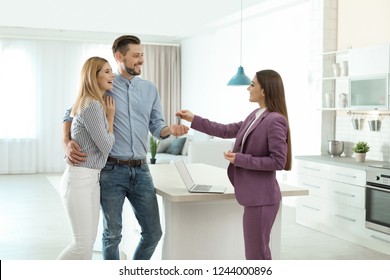 Female real estate agent giving house key to couple indoors - Powered by Shutterstock