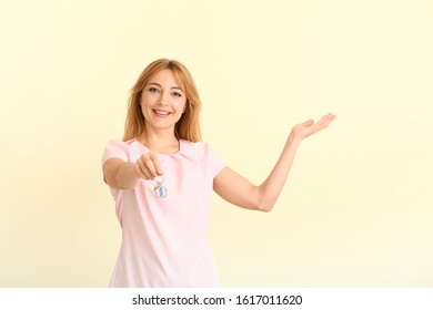 Female real estate agent with key showing something on color background - Shutterstock ID 1617011620