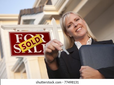 Female Real Estate Agent With Keys In Front Of Sold Sign And Beautiful House.