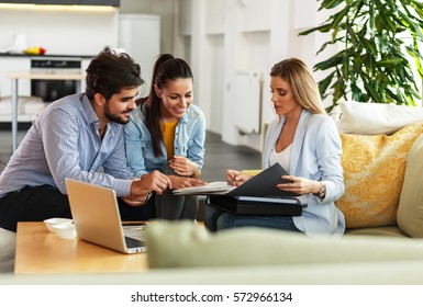 Female Real Estate agent offer home ownership and life insurance to young couple. - Shutterstock ID 572966134