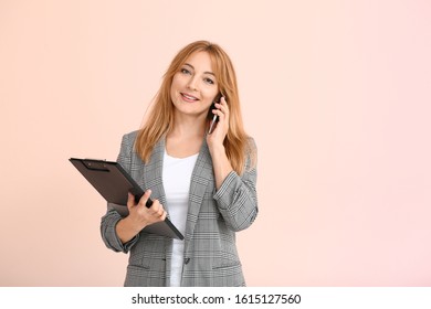 Female Real Estate Agent Talking By Mobile Phone On Color Background